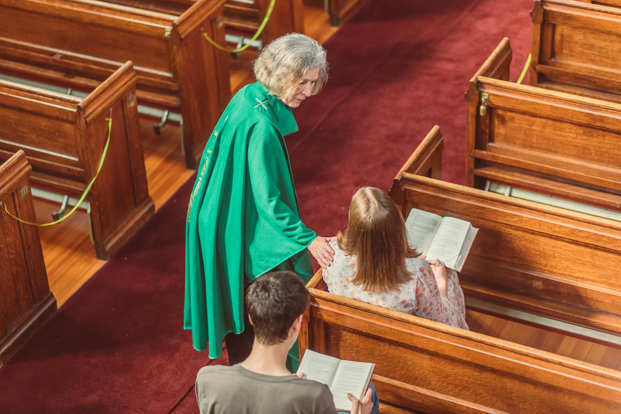 A clergy member conversing with parishioners in a church setting.